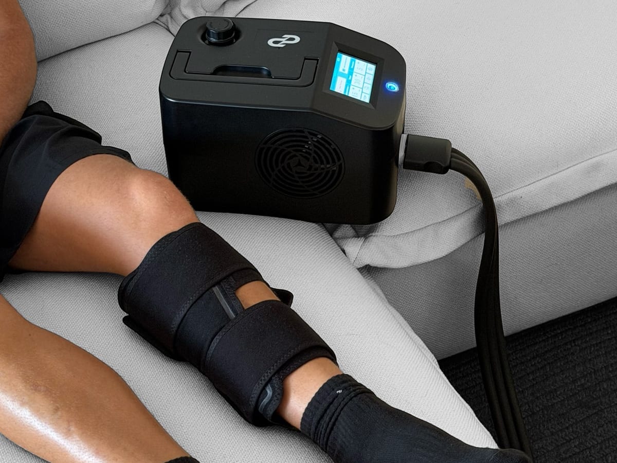 The Pulse One ice and compression unit beside a leg with a garment fitted, connected by a hose